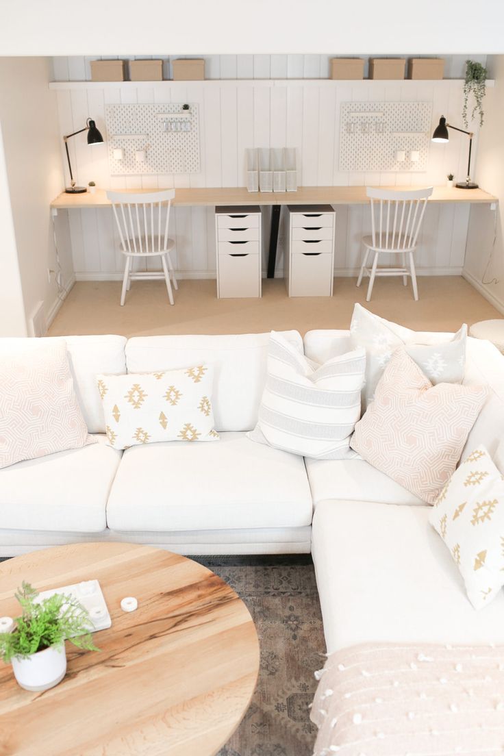 a living room filled with white furniture and lots of pillows