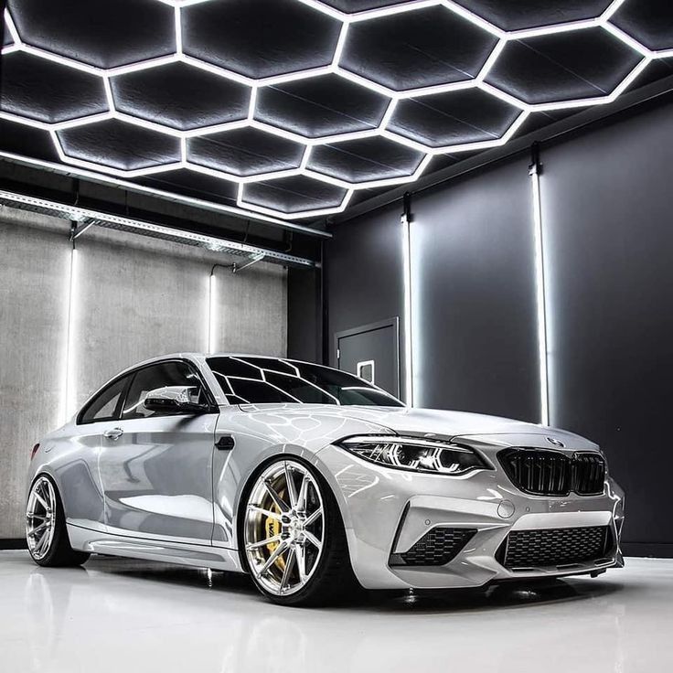 a silver car parked in front of a wall with lights on it's sides