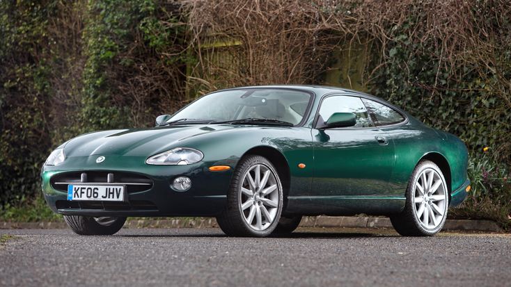 a green sports car parked in front of some bushes