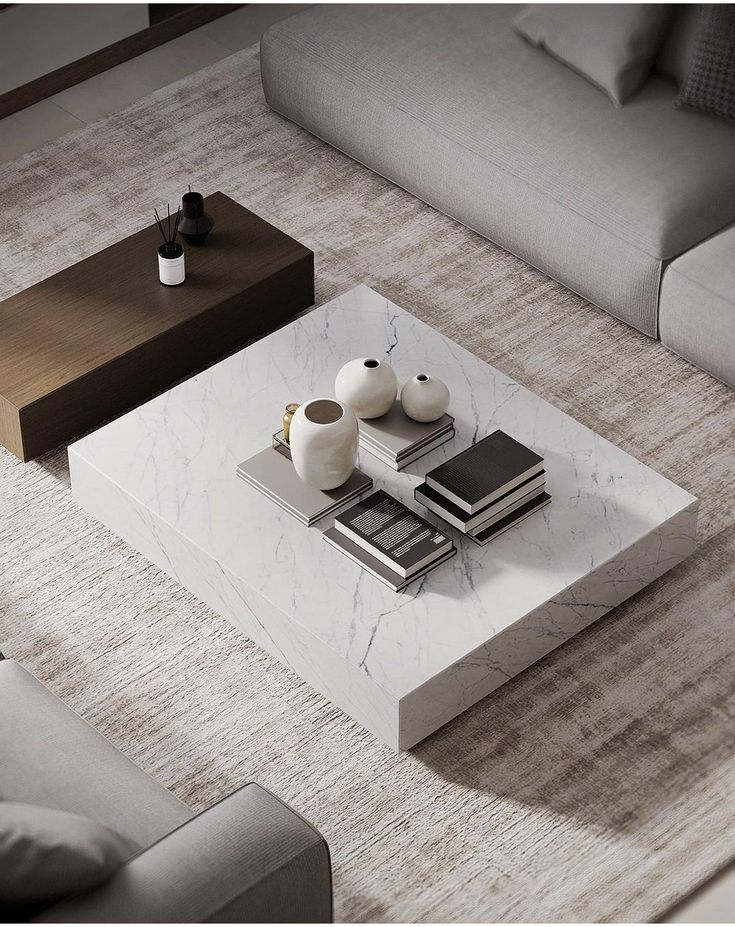 a marble coffee table with two white vases on it and books sitting on top