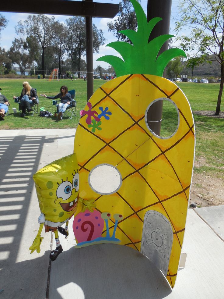 a cardboard cut out of a yellow pineapple sitting on top of a wooden bench