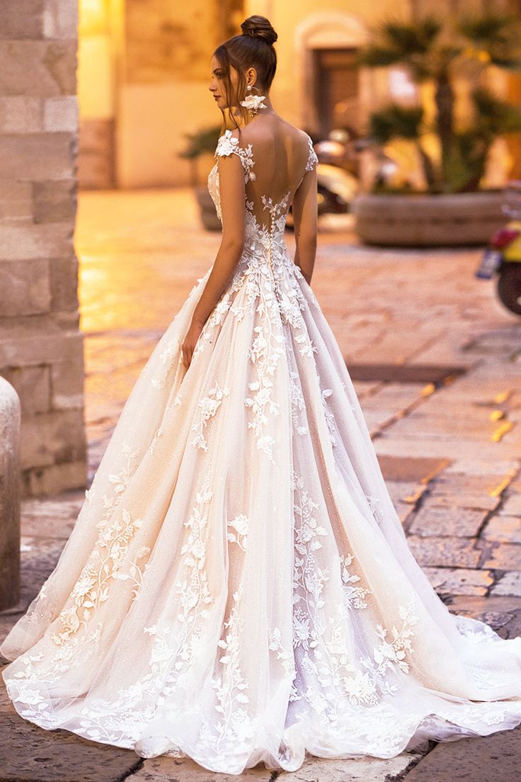 a woman in a wedding dress is standing on the street at night with her back turned to the camera