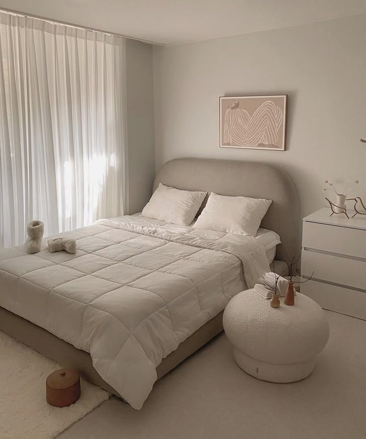 a bedroom with a large bed and white curtains