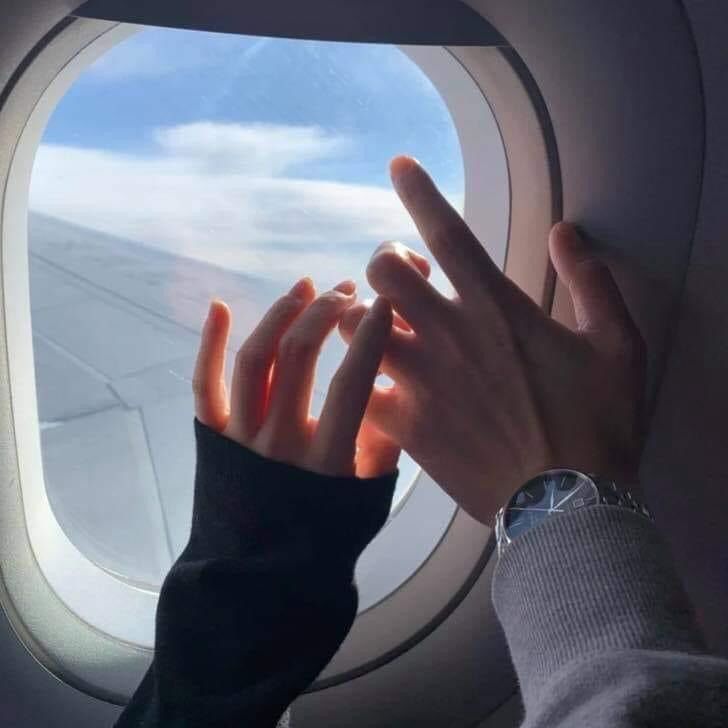 a person's hand reaching out an airplane window