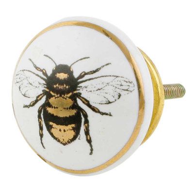 a white and gold knob with a bee on it