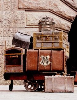 several suitcases stacked on top of each other in front of a building with a birdcage