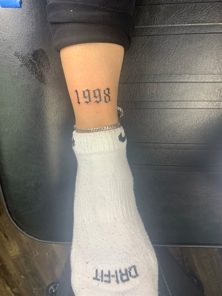 a person with a small tattoo on their left leg and the number 989 written on her right ankle