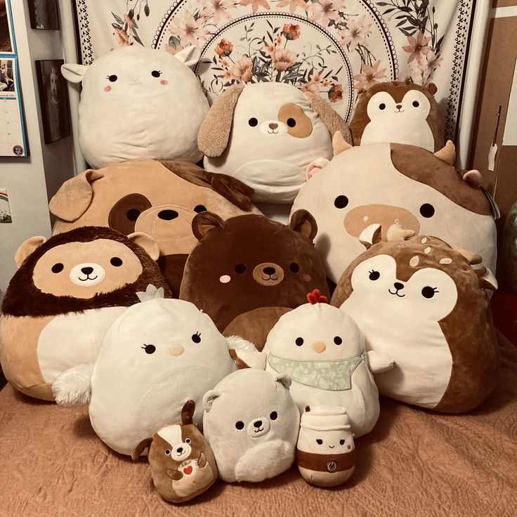 a pile of stuffed animals sitting on top of a bed next to each other in front of a wall