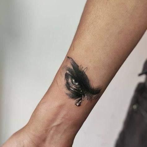 a woman's wrist with an eye tattoo on the left side of her arm