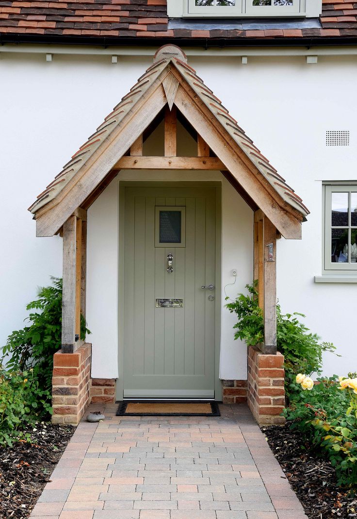 a white house with a green front door and brick walkway leading to the entrance area