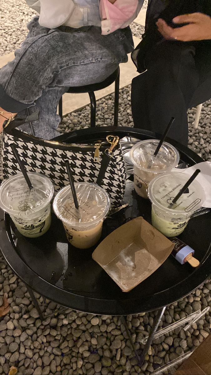 there are three drinks on the table with straws in their cups and one is empty