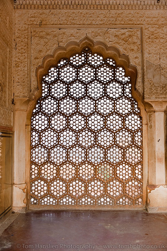 an intricately carved window in the middle of a building with tilework on it