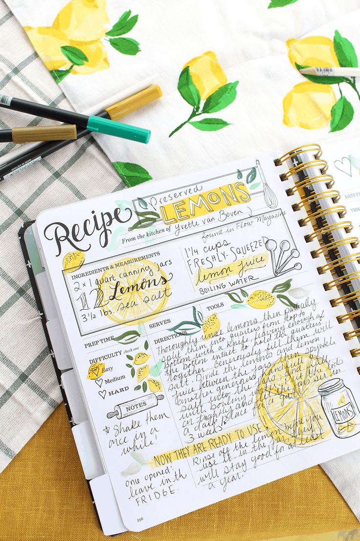 a recipe book with lemons on it next to markers and pens, along with other kitchen utensils