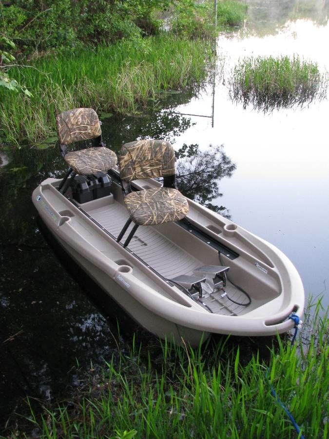 a small boat sitting on the side of a river next to grass and trees in the water