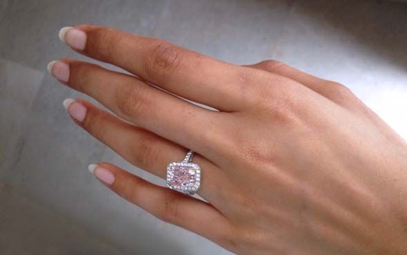 a woman's hand with a pink diamond ring on her left hand and an engagement band