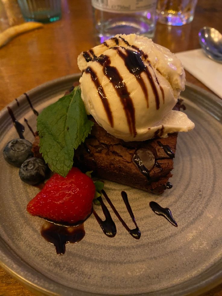 a dessert with ice cream, strawberries and chocolate sauce on a plate at a restaurant