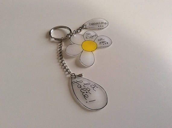 a keychain with a flower and some words on the front, sitting on a white surface