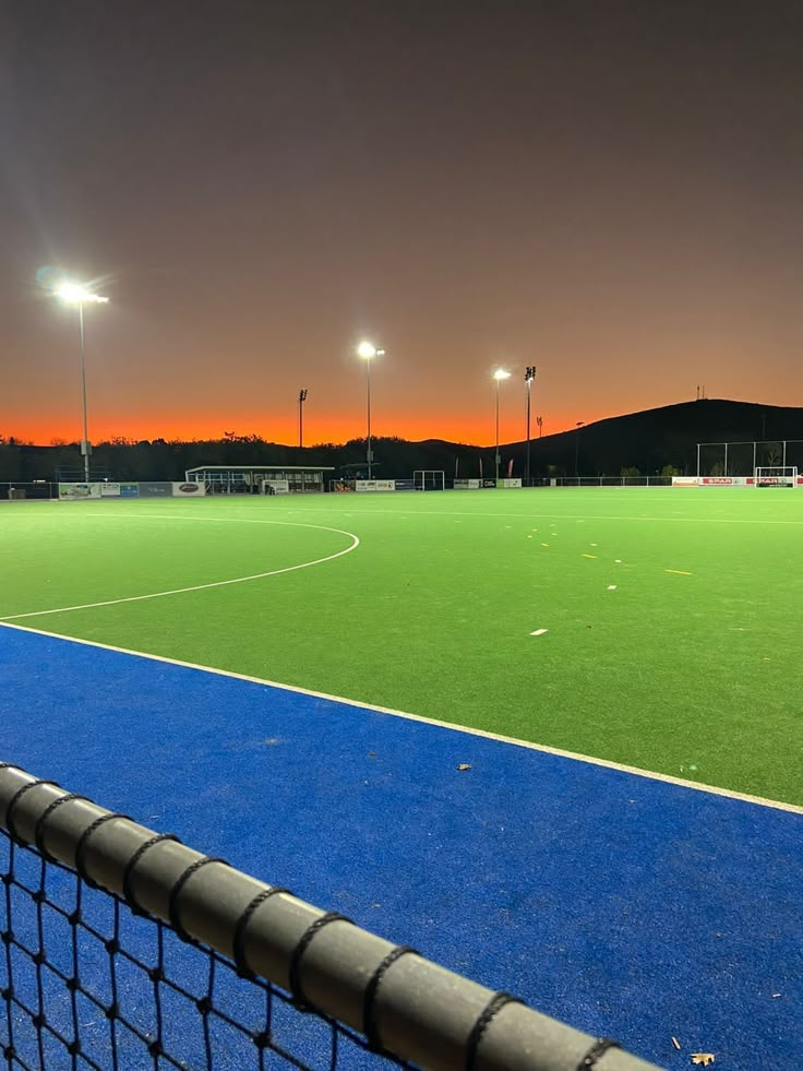 an empty soccer field at night with lights on