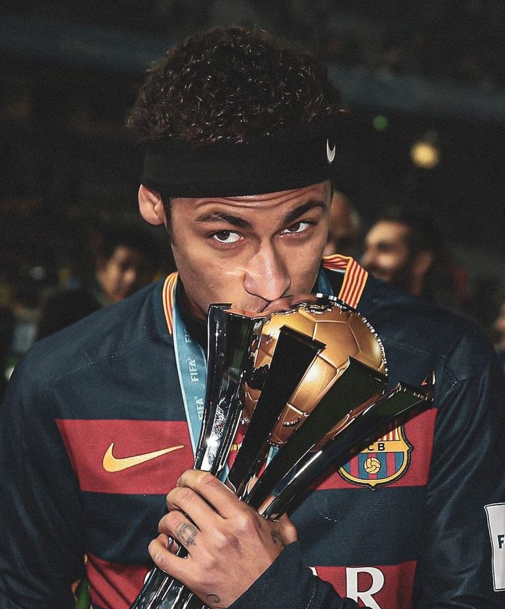 a young man holding up trophies in front of his face and looking at the camera