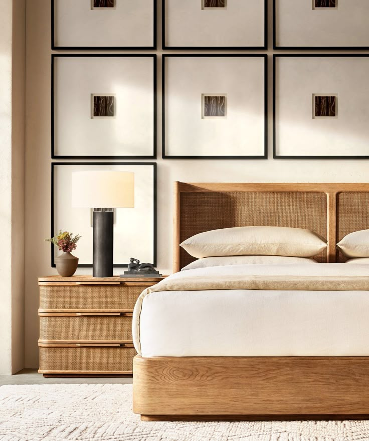 a bed with white sheets and pillows in front of four framed pictures on the wall