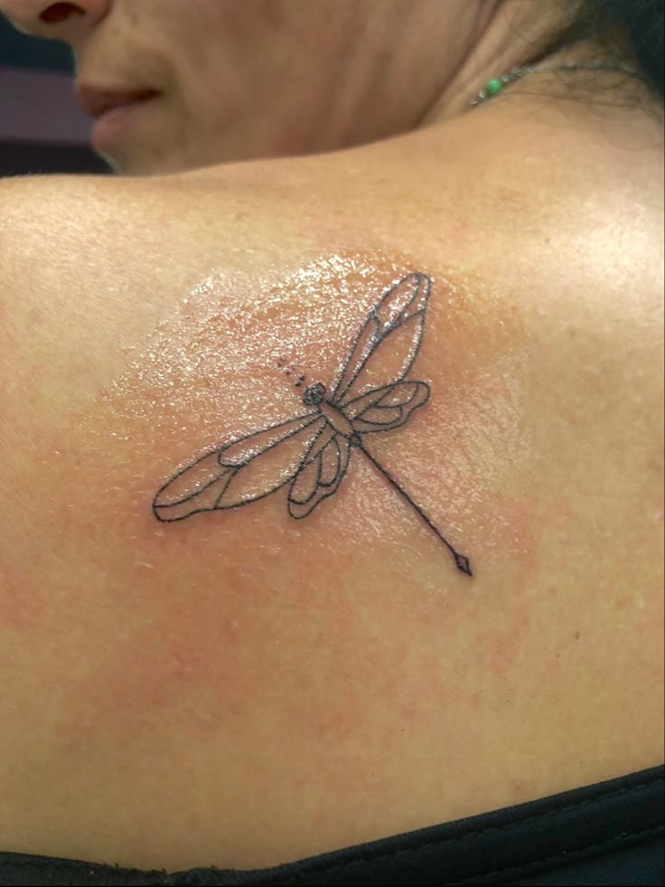 a woman with a dragonfly tattoo on her shoulder