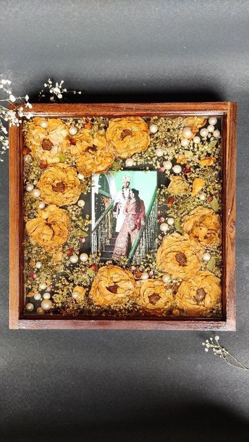 a wooden frame with an image of a man and woman surrounded by flowers on it