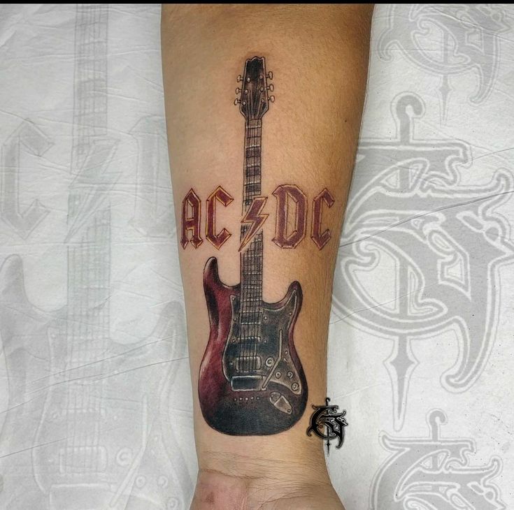 a man's arm with a guitar tattoo that reads ac / dc on it