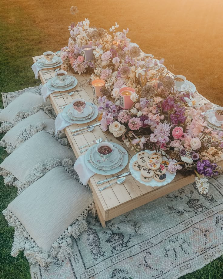 a table set up with flowers and plates on it for a tea party or brunch