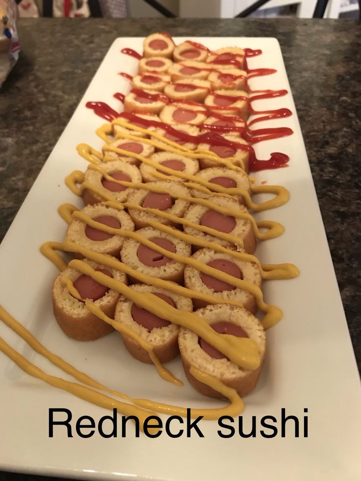 a long white plate topped with hot dogs covered in ketchup and mustard sauce