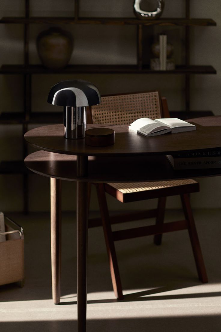 a wooden table with a book on top of it next to a chair and shelf