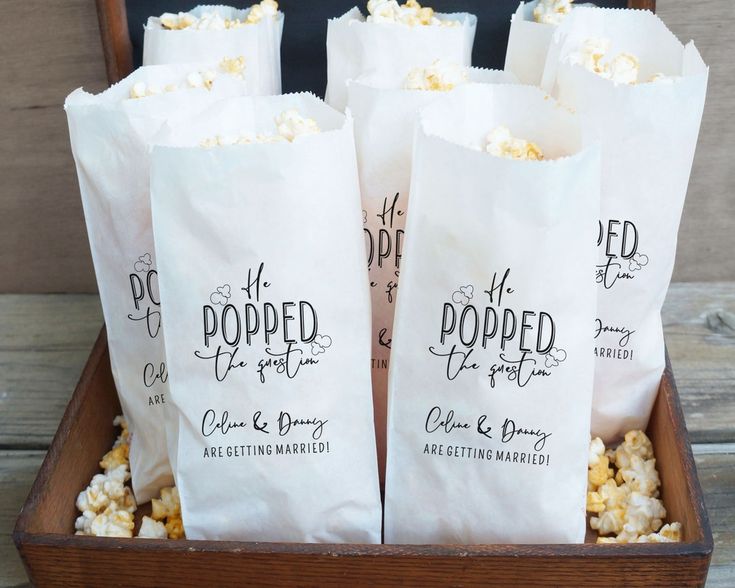 four bags of popcorn sitting in a wooden box