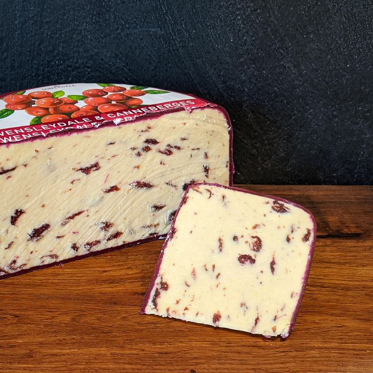 a piece of cheese sitting on top of a wooden table next to a slice of bread