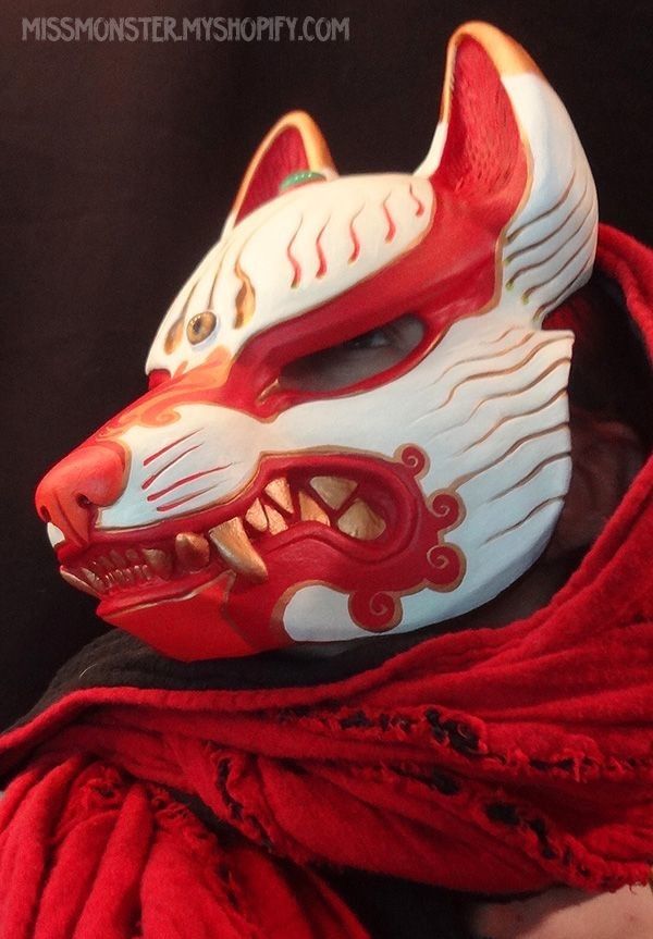 a red and white mask with an animal's face on it, sitting on top of a blanket