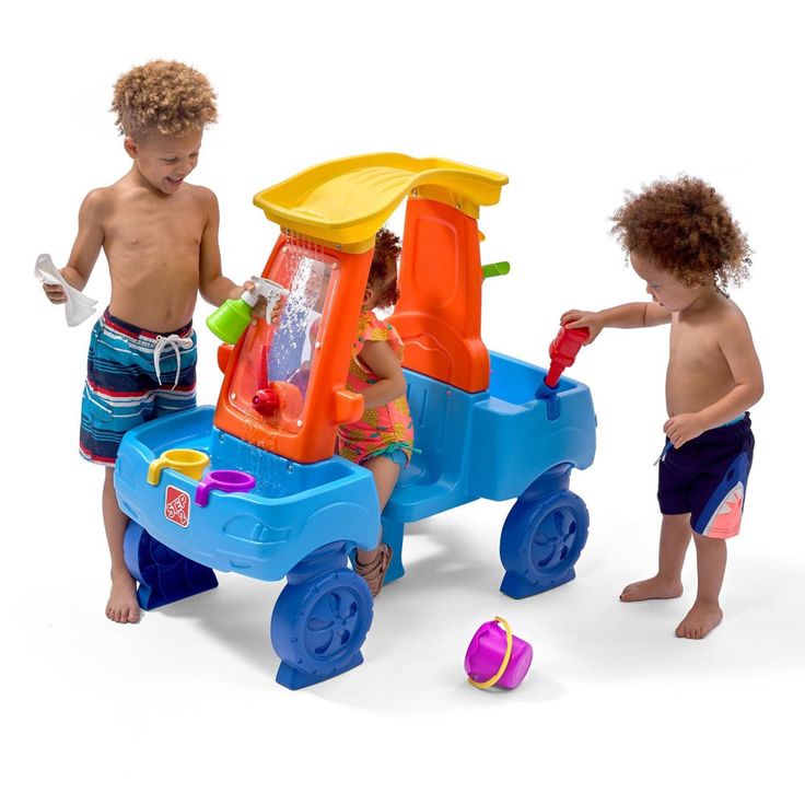 two young children playing with a toy truck and water fountain on a white back ground