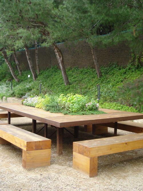 an image of a table and benches in the middle of a field with trees behind it