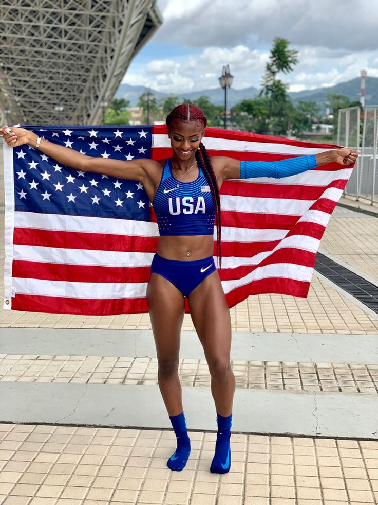 a female athlete is posing in front of an american flag