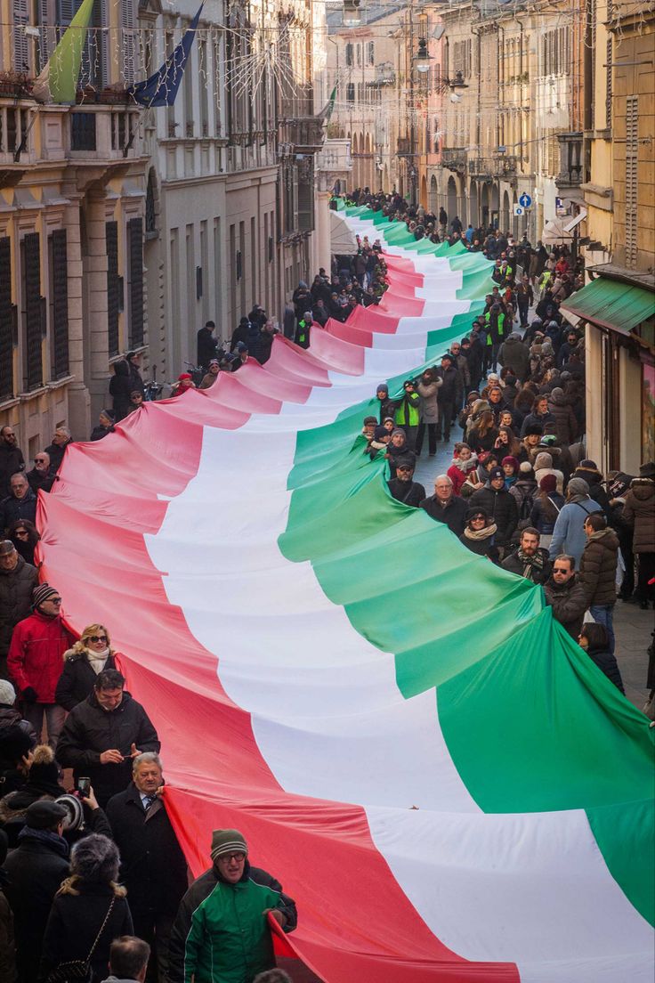 a large italian flag is being carried down the street by people in green and white