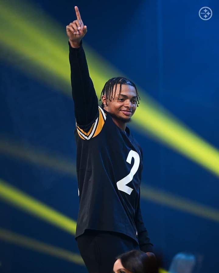 a man with dreadlocks waves to the crowd at a sporting event on stage