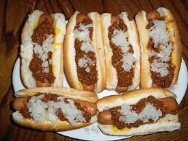 four hot dogs with chili and cheese on them