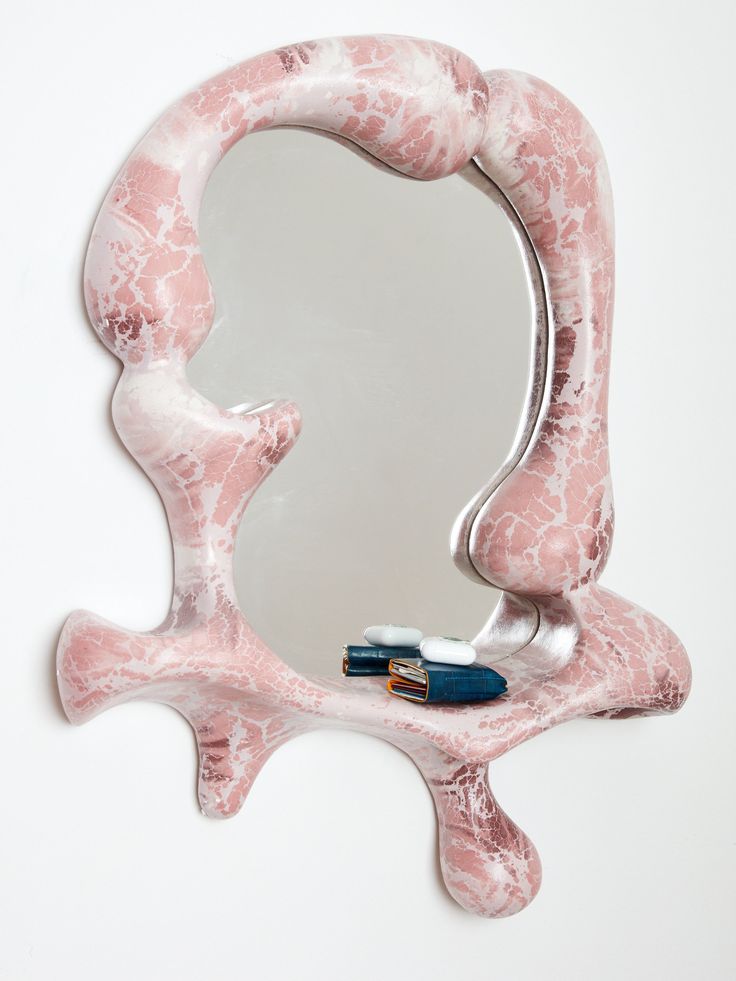 a pink and white marbled vanity mirror with a blue pen resting on it's side