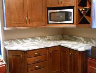 a kitchen with wooden cabinets and white marble counter tops in front of a stainless steel microwave oven