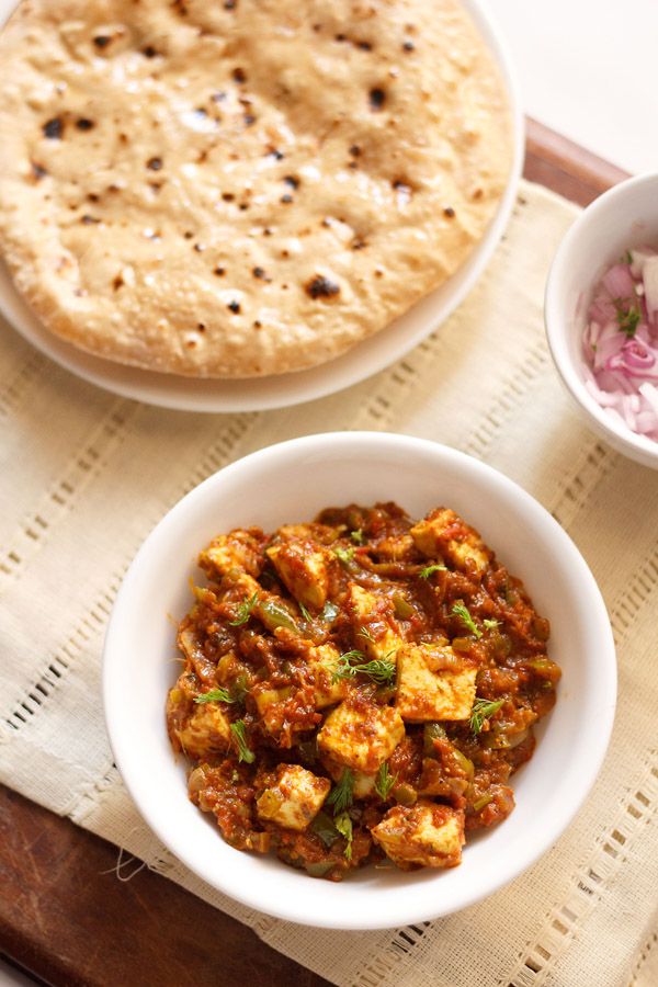 two bowls filled with food sitting on top of a wooden tray next to a pita bread