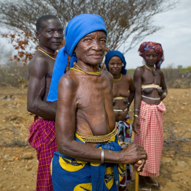 some people are standing in the dirt and one is wearing a blue headdress