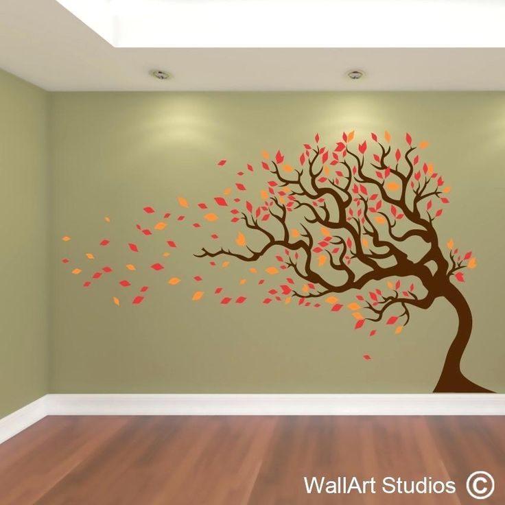 a tree with leaves blowing in the wind on a wall sticker that is part of a living room