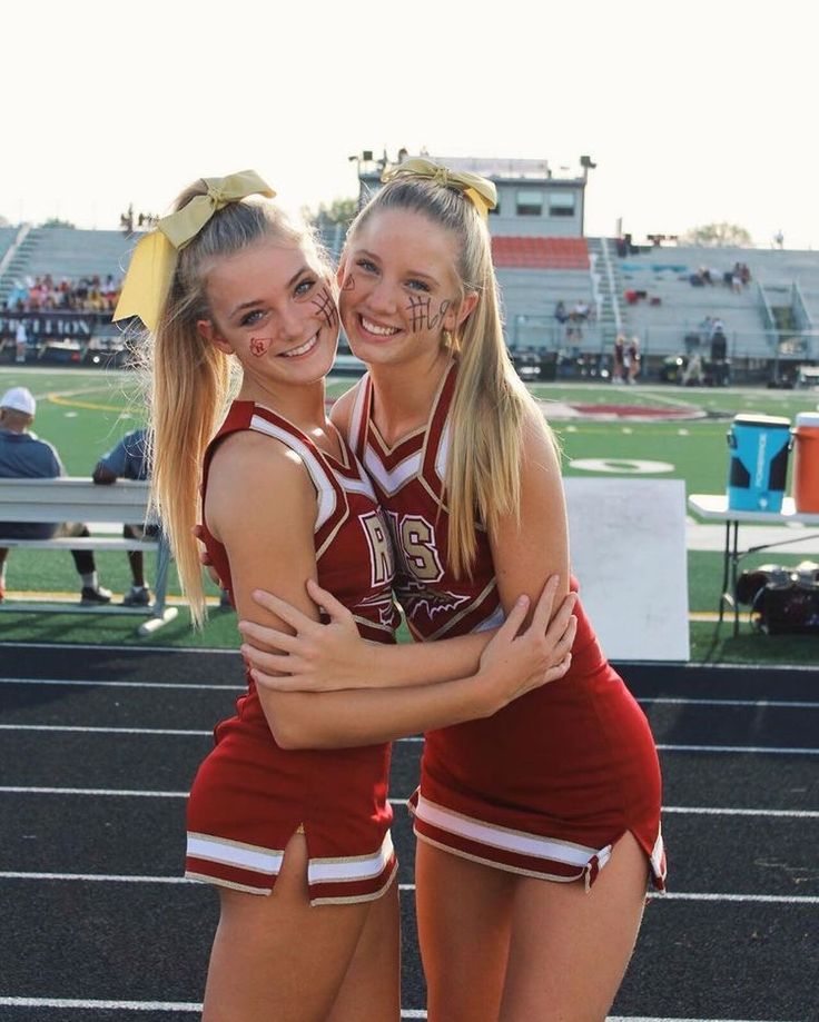 two cheerleaders hugging each other on the sidelines