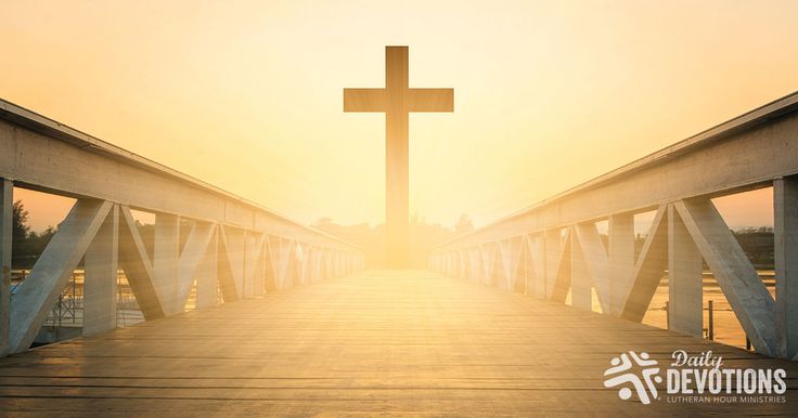 a cross on top of a bridge with the sun setting in the distance behind it