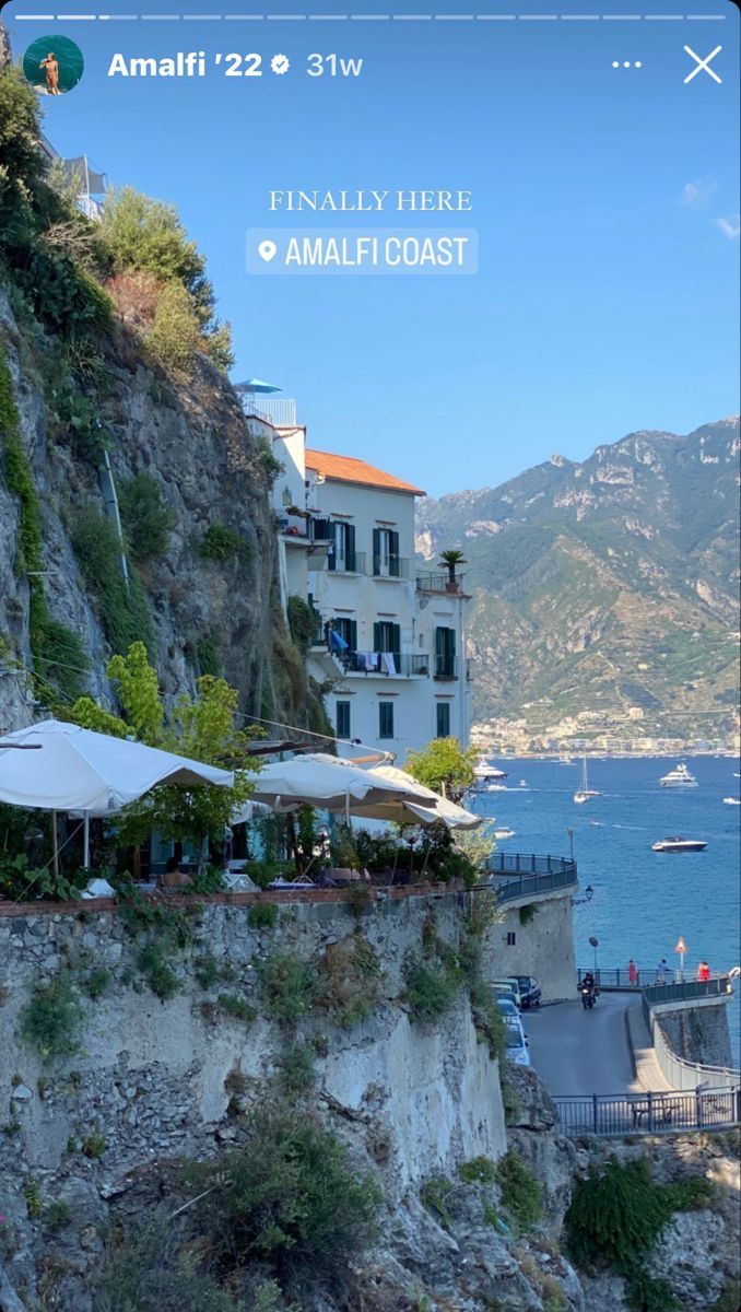 an iphone photo of the amalfi coast with boats in the water and buildings on the cliff