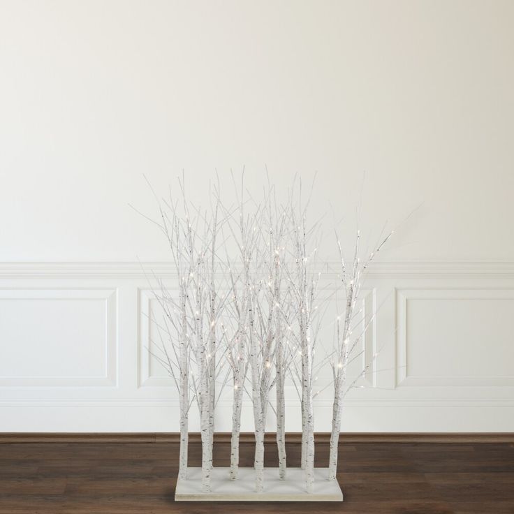 a group of white trees sitting on top of a wooden floor next to a wall