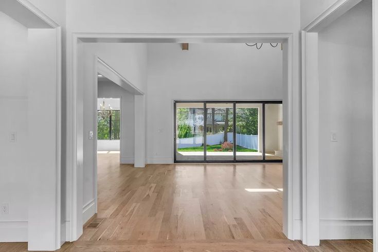 an empty living room with wood floors and white walls is seen from the entry way