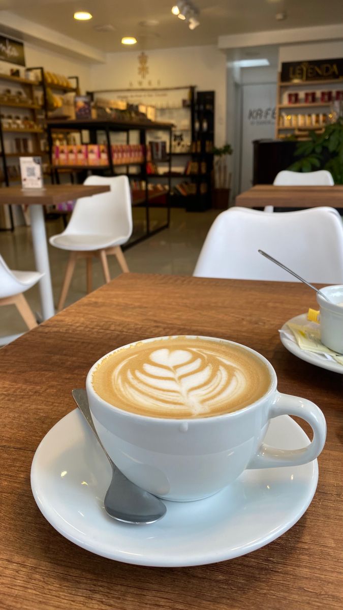 a cappuccino sits on a saucer in a coffee shop